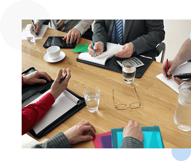 A group of people sitting at a table with papers.